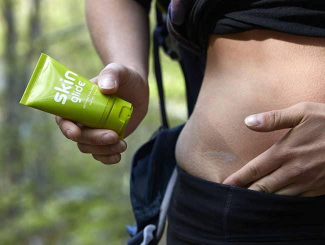 close up of a model applying the BodyGlide anti-friction cream to their hip where their leggings might chafe against the skin