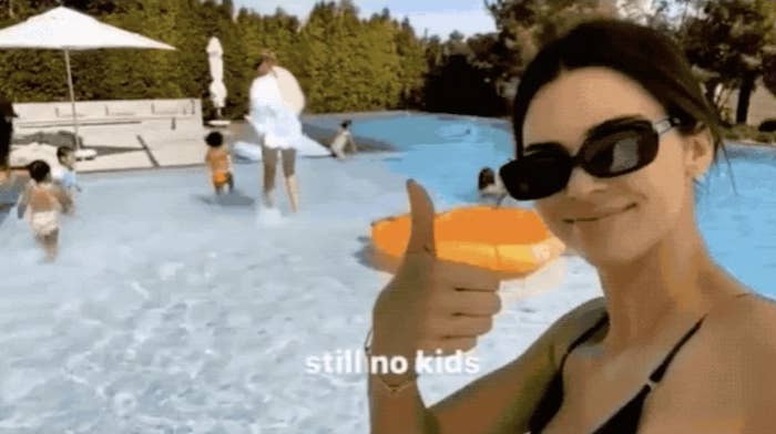 Kendall giving a thumbs-up in front of a pool with the caption "still no kids"