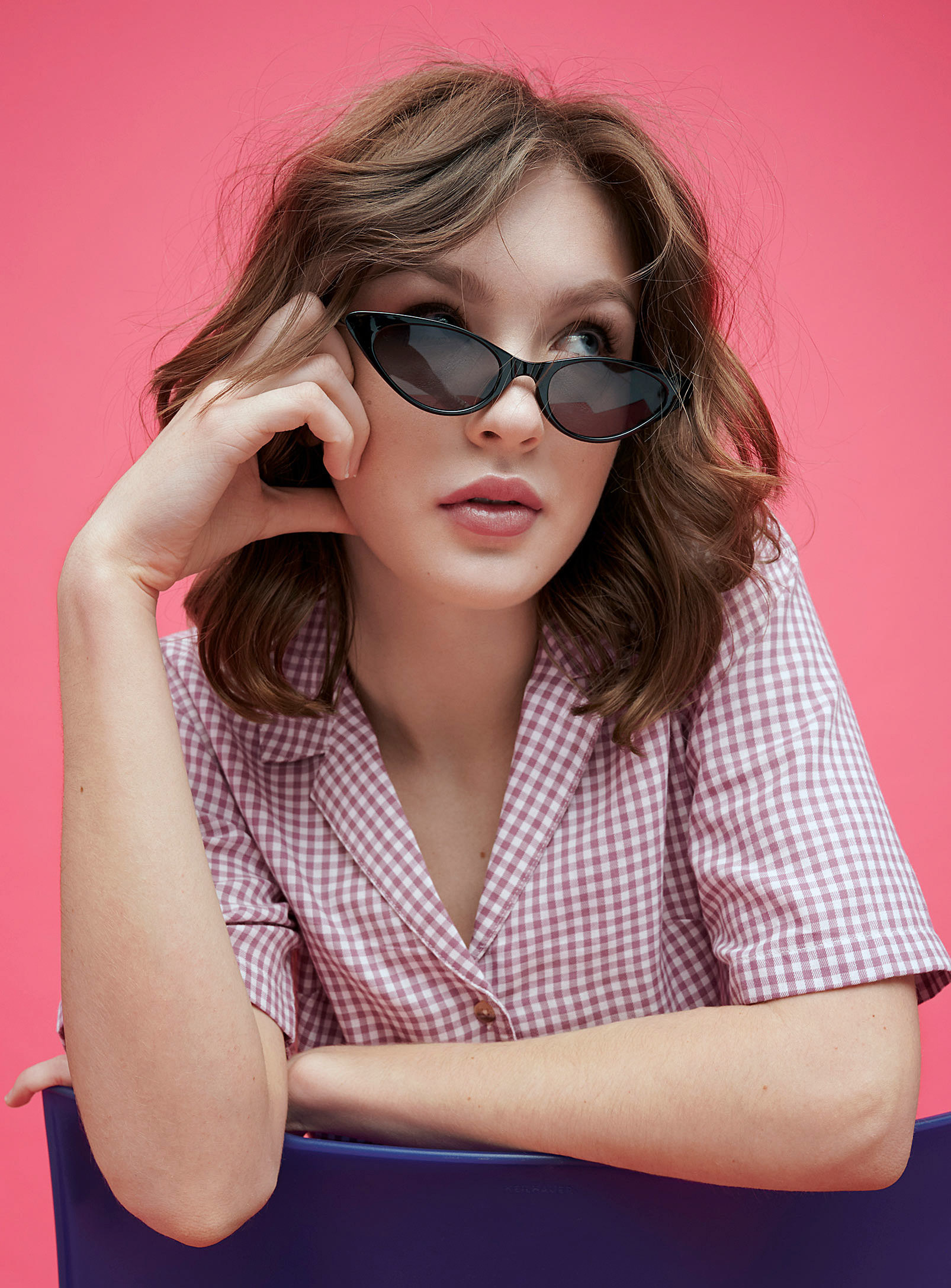 A person wearing tiny cat-eye sunglasses