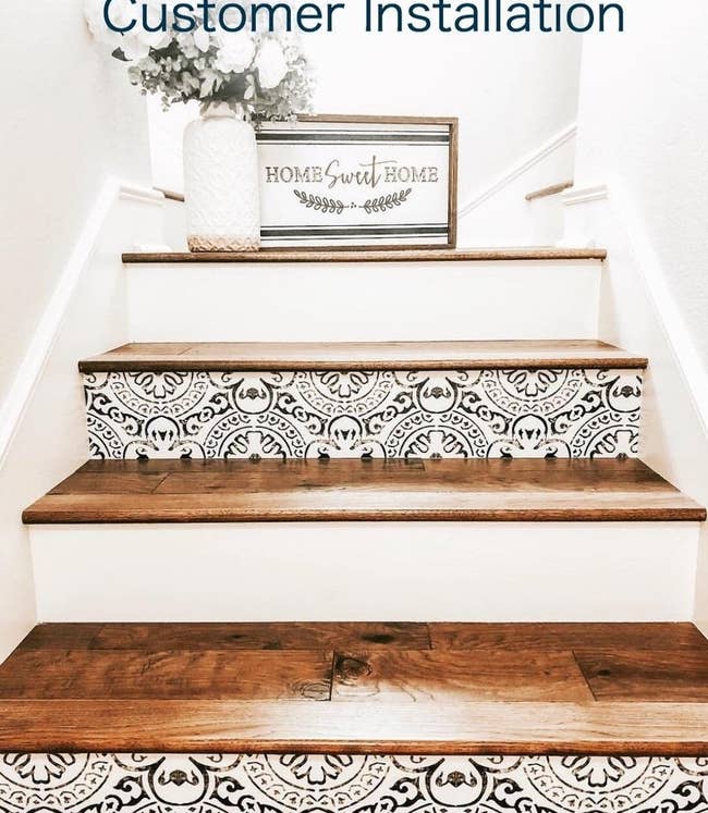white stairs with dark wood treads; ever other stair riser features a faux-distressed black geometric pattern on white