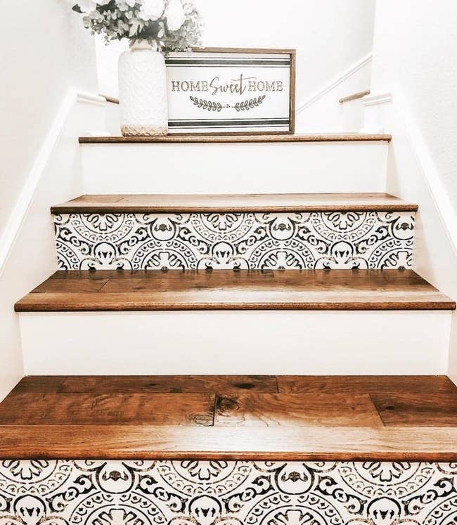 white stairs with dark wood treads; ever other stair riser features a faux-distressed black geometric pattern on white