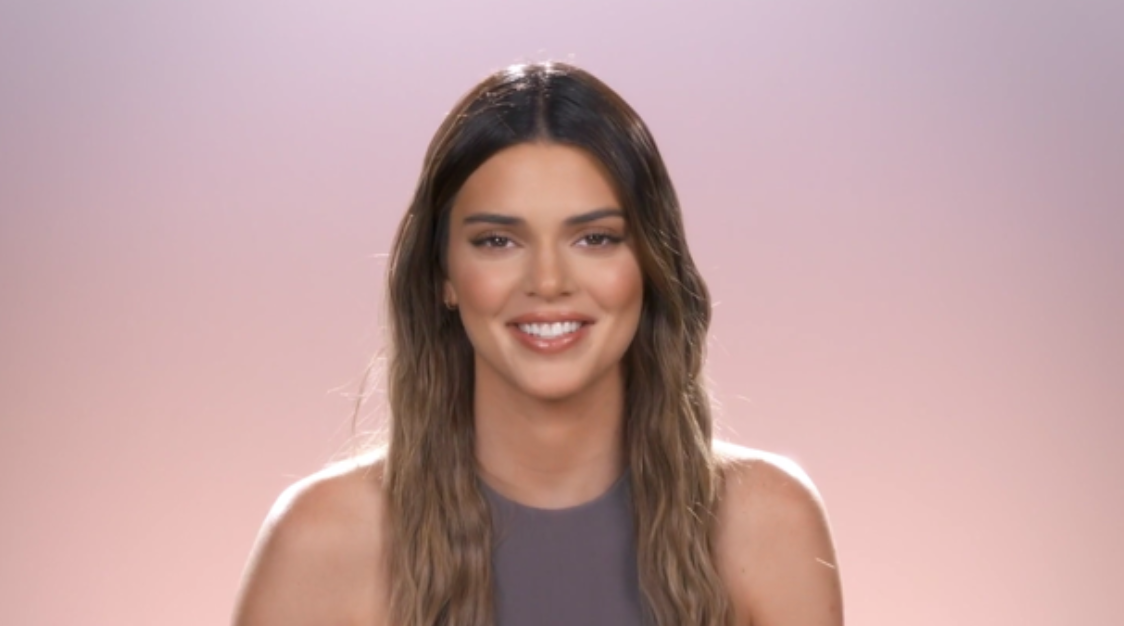 Kendall smiling in front of a pink and purple background