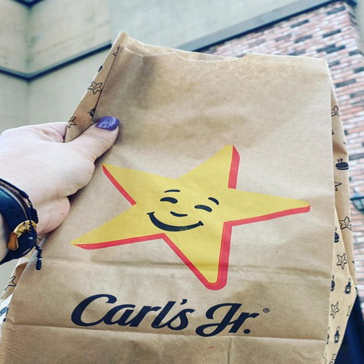 A fast food to-go bag wit the carl's jr logo on it that has a star and cursive font