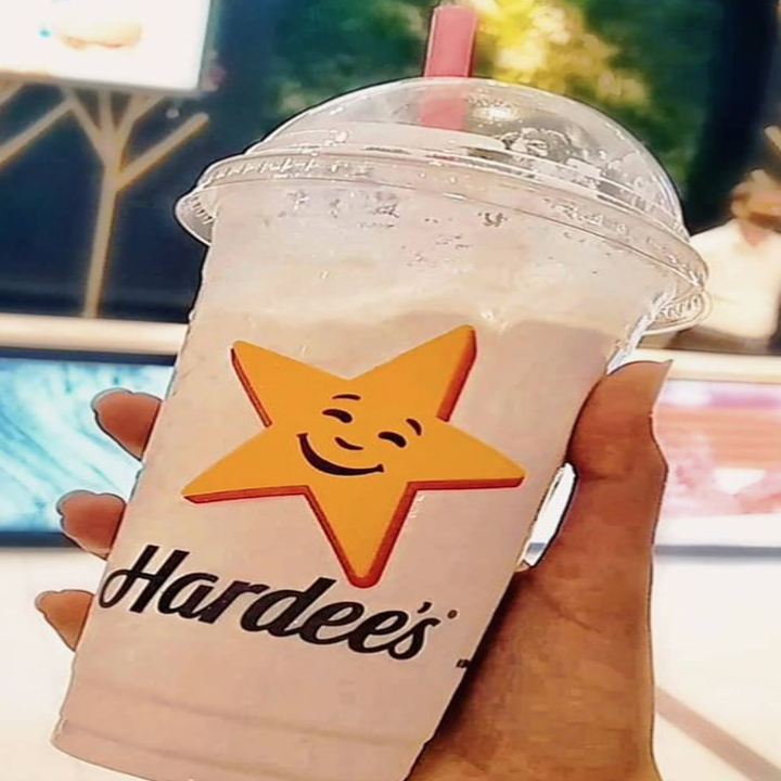 A plastic milkshake cup with the hardee's logo on it that has a star and cursive font