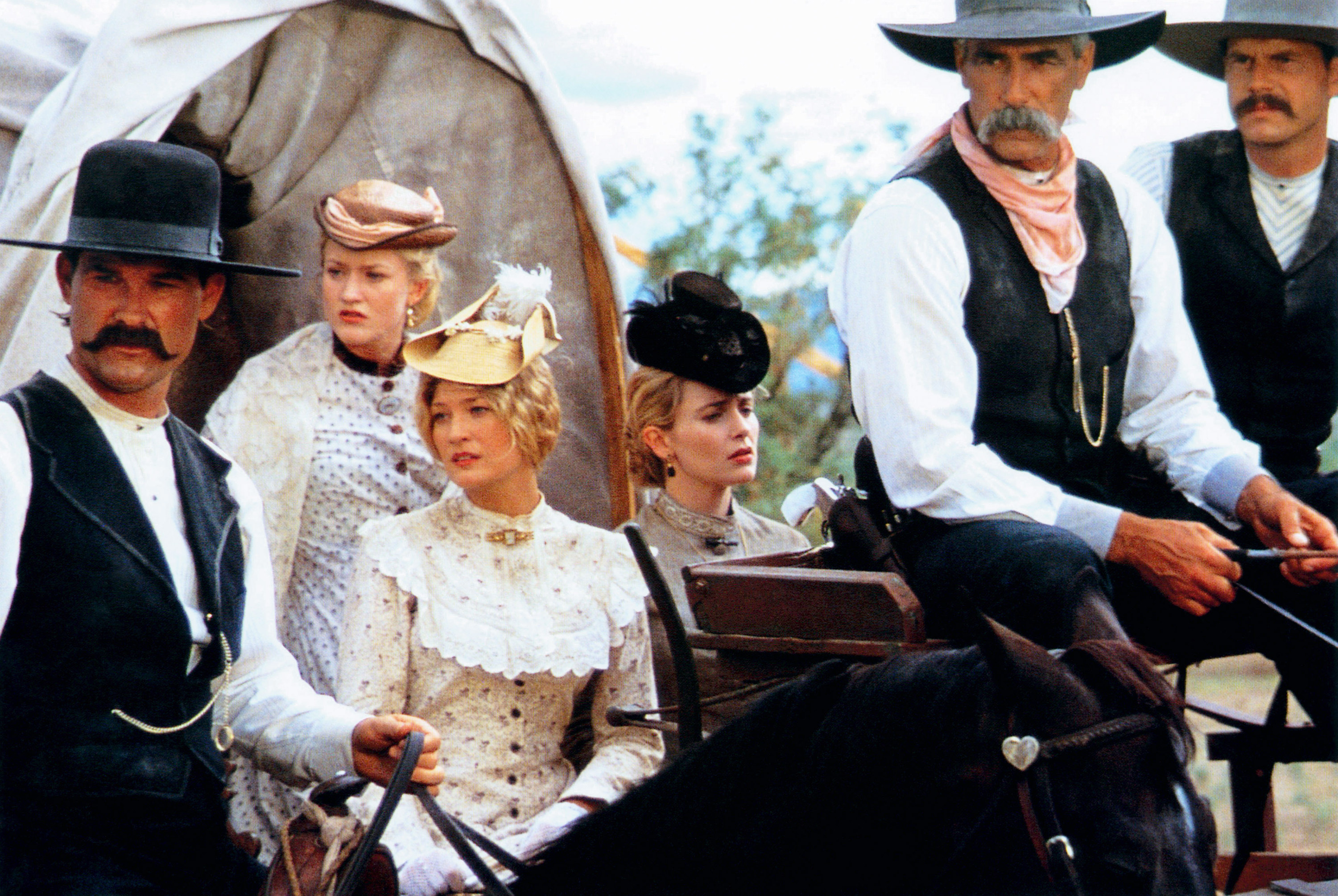 still shot of the cast from tombstone looking in one direction while using a horse carriage