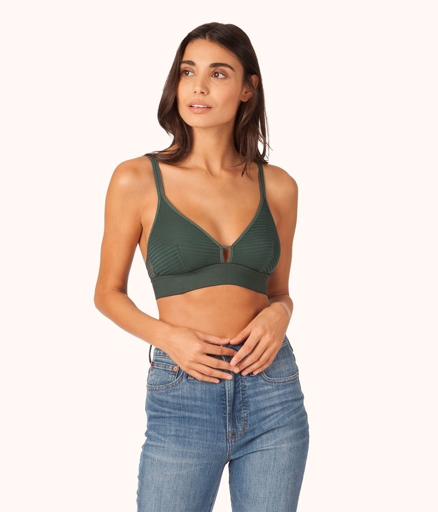a model wearing the emerald stripe mesh bralette with jeans