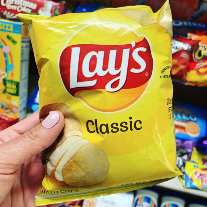 A bag of Lay's potato chips with a logo that looks like a sun and a red ribbon going across it with specific font