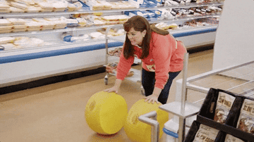 Character rolling two giant wheels of cheese through the grocery store