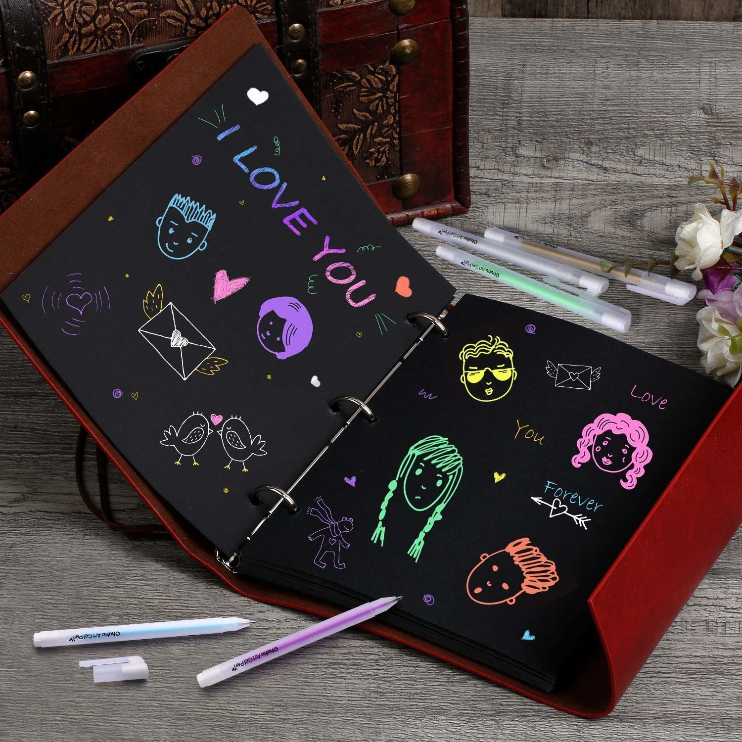 A notebook with black pages filled with colourful drawings created with the gel pens.