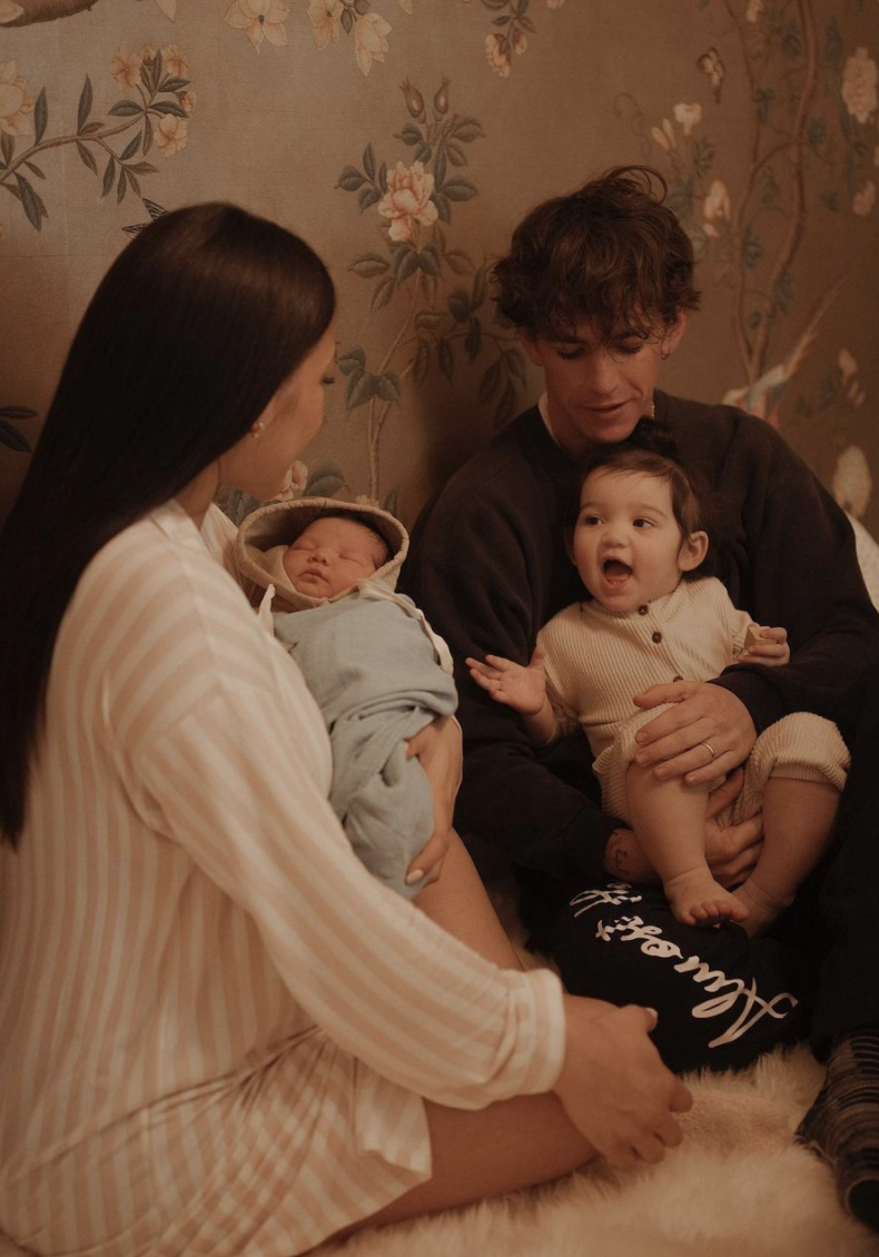 Cassie holding her newborn as her husband and her other daughter look on