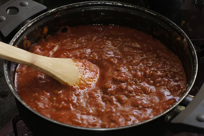Pan full of chunky tomato sauce with wooden spoon on top