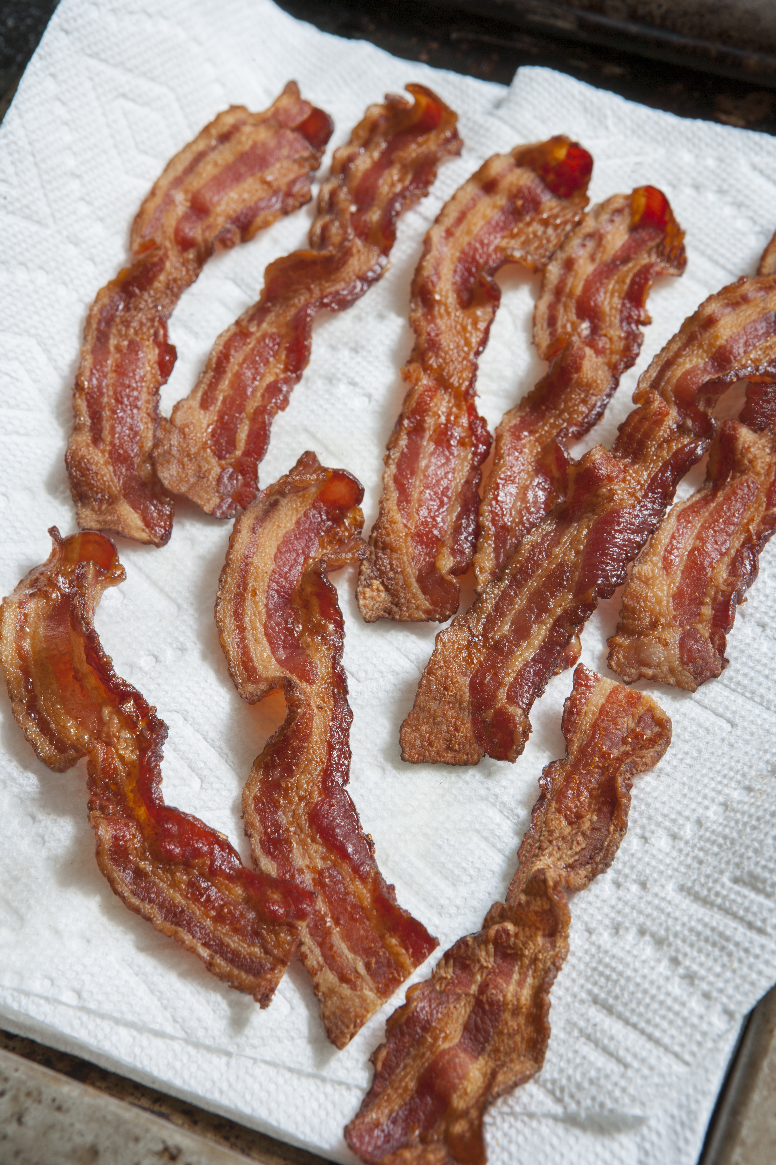 Paper towel covered with strips of cooked crispy bacon