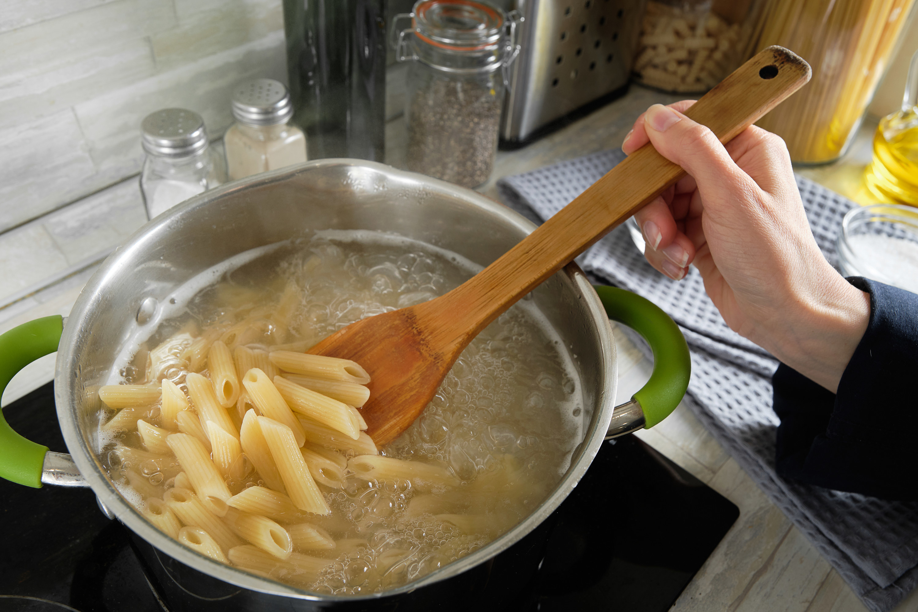 Pasta spoon stirring a bit of pasta in pot of boiling water