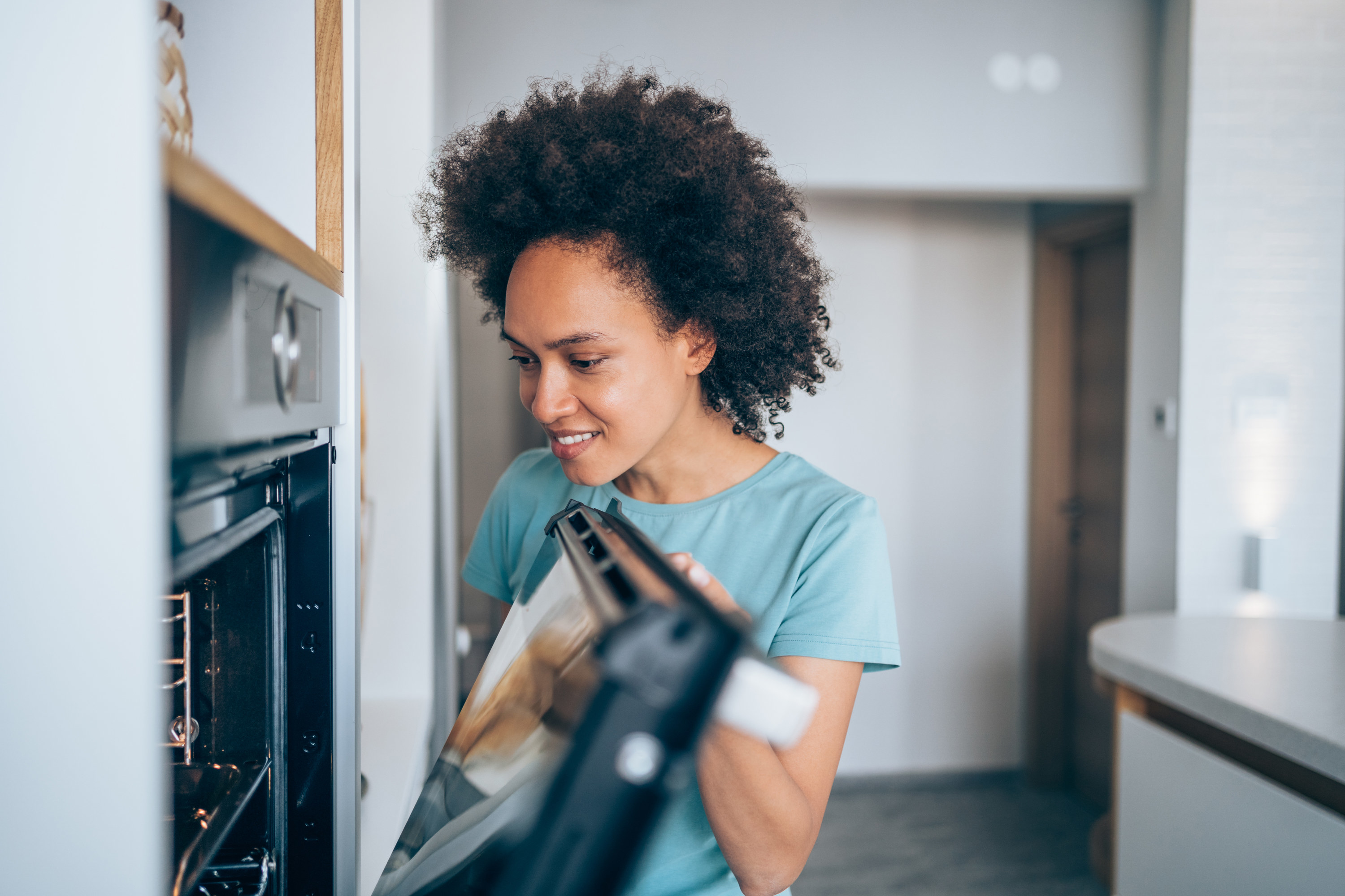 Woman opening oven to check inside it