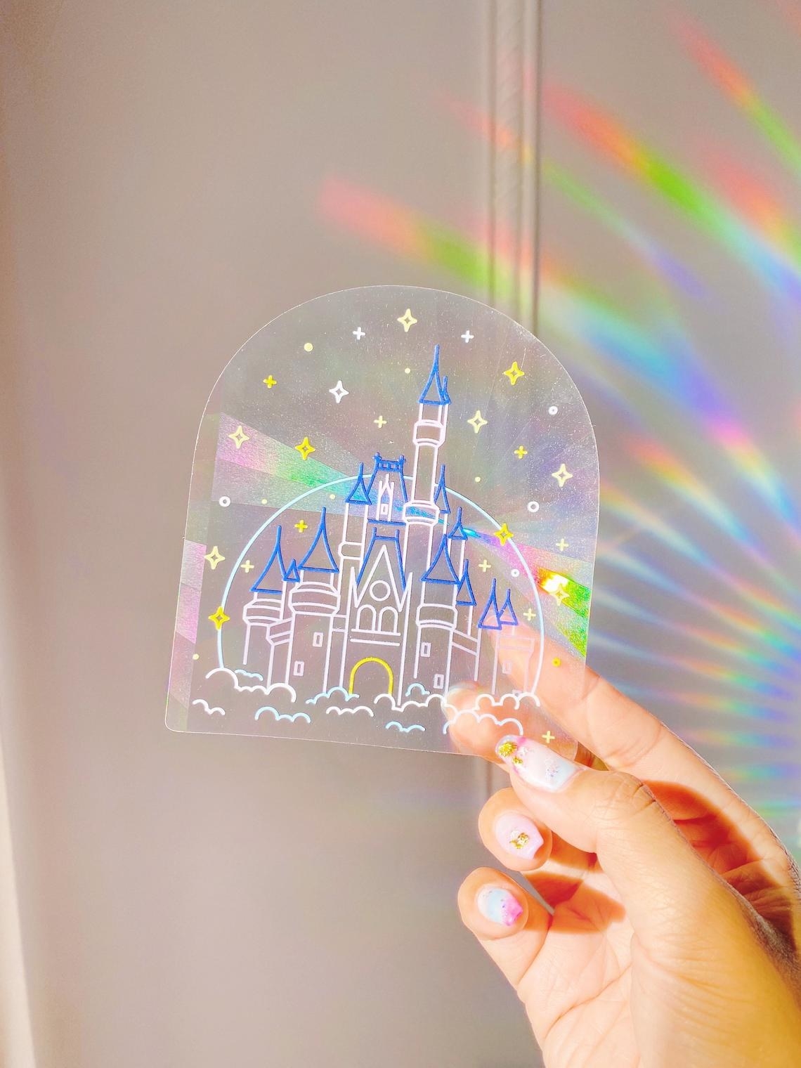 sticker with illustration of cinderellas castle that refracts light to create rainbows 