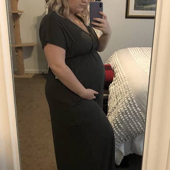 the same reviewer holding her baby bump in the dress