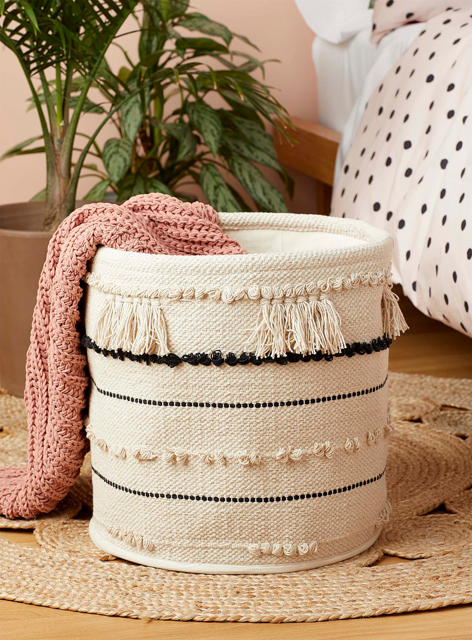 A woven basket with a blanket hanging off the edge