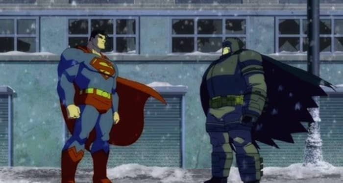 Superman and Batman facing off in front of snow-covered building