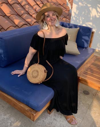 reviewer wearing the black dress with straw bag and fedora 