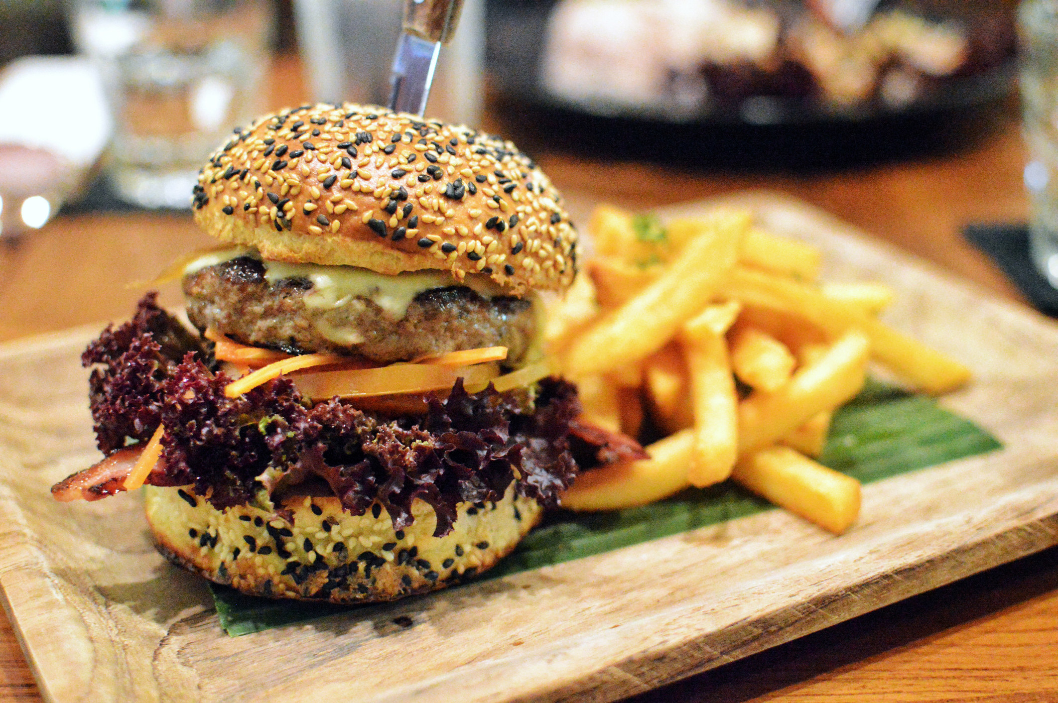 A delicious hamburger and fries are arranged on a wooden board.