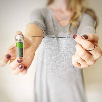 A model holding out the glass tube filled with floss and pulling the floss out in a long strand 
