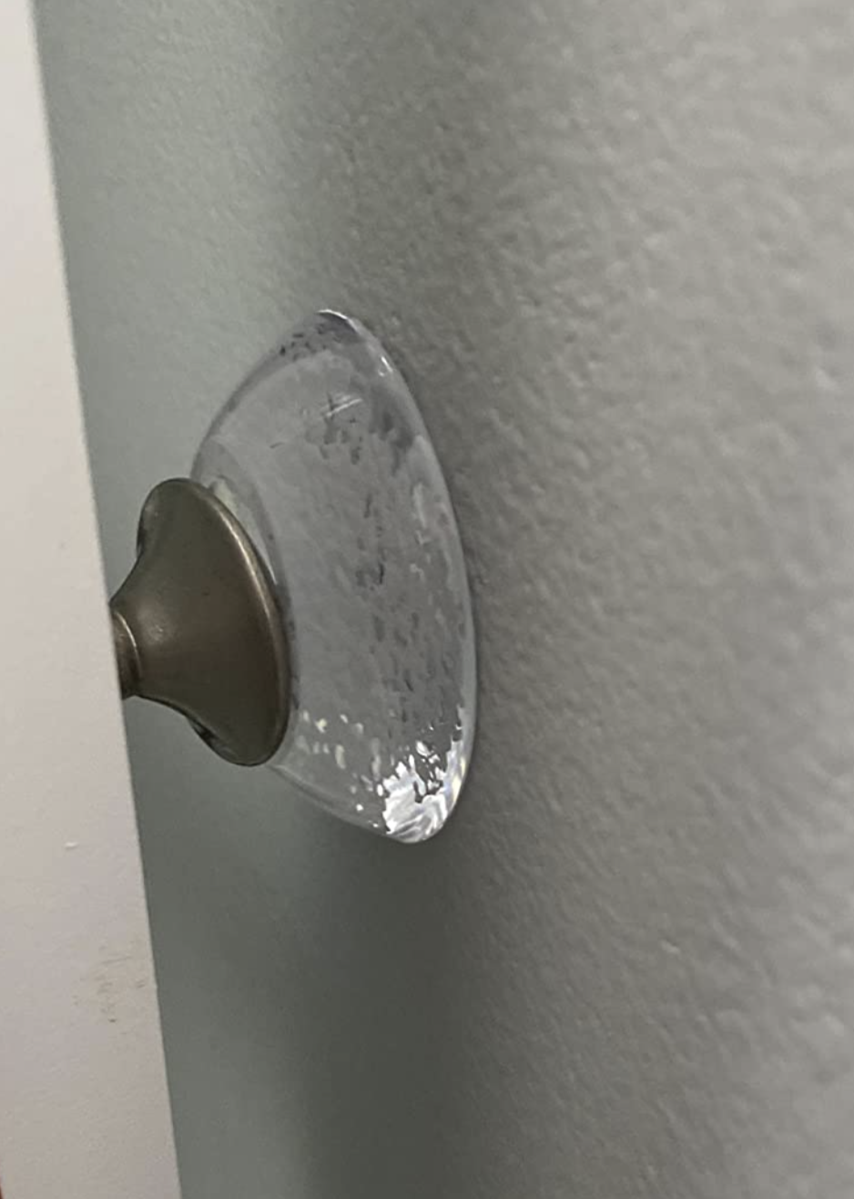 round clear doorstopper on the wall actually stopping a doorknob from touching the wall