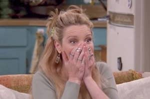 Phoebe from "Friends" raising her eyebrows and covering her mouth with her hands