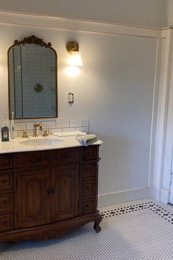 golden mirror with extra gilding at the top of it and it's hanging over a bathroom sink