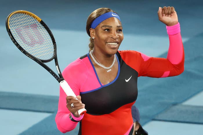 Serena smiles while holding her tennis racket on the court 