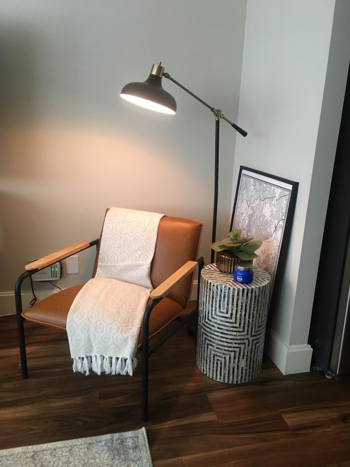 a reviewer&#x27;s tan chair with a throw blanket draped over it