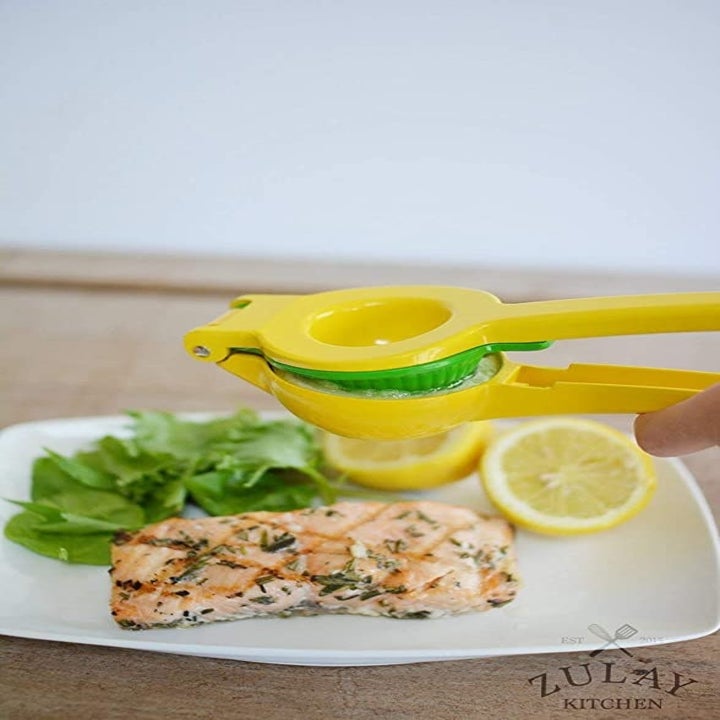 The juicer is being used to squeeze lemon juice on fish