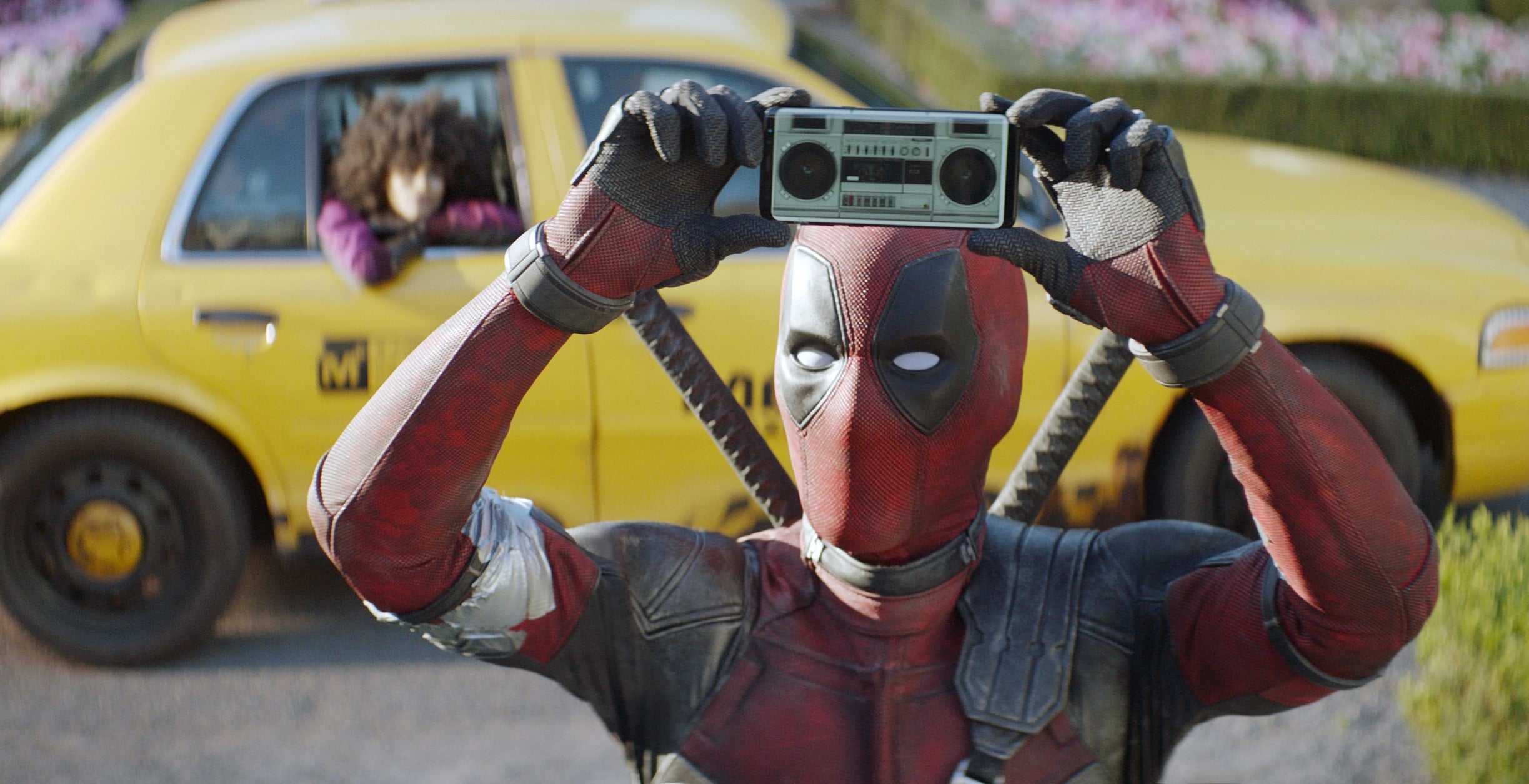 Ryan Reynolds as Deadpool holding a mini boom box