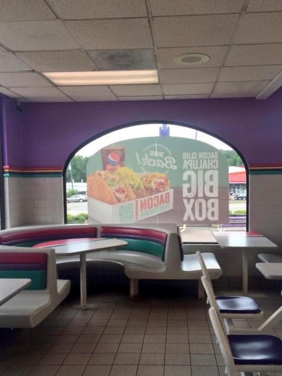 The inside of a Taco Bell with purple, pink, and teal interiors