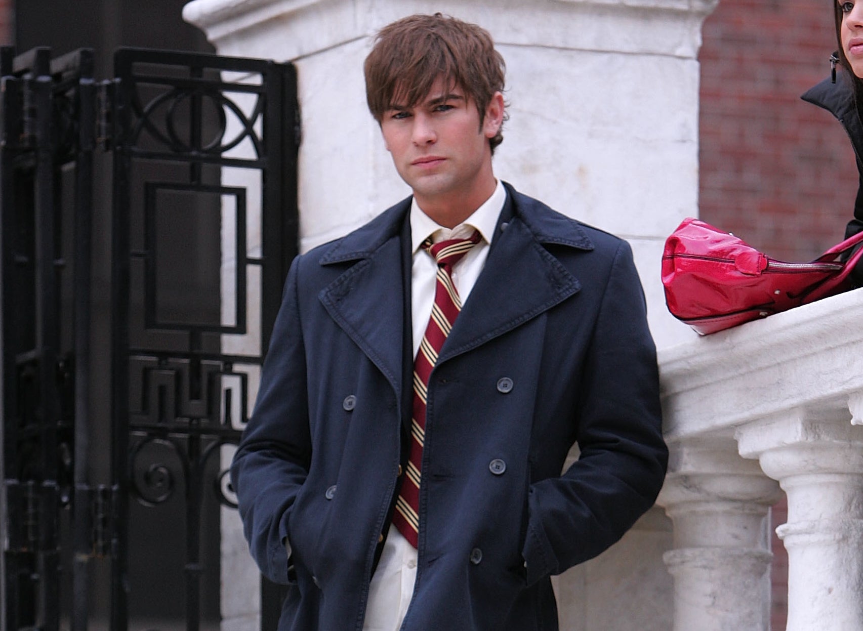 Nate stands on a marble staircase outside of a building while filming the show 
