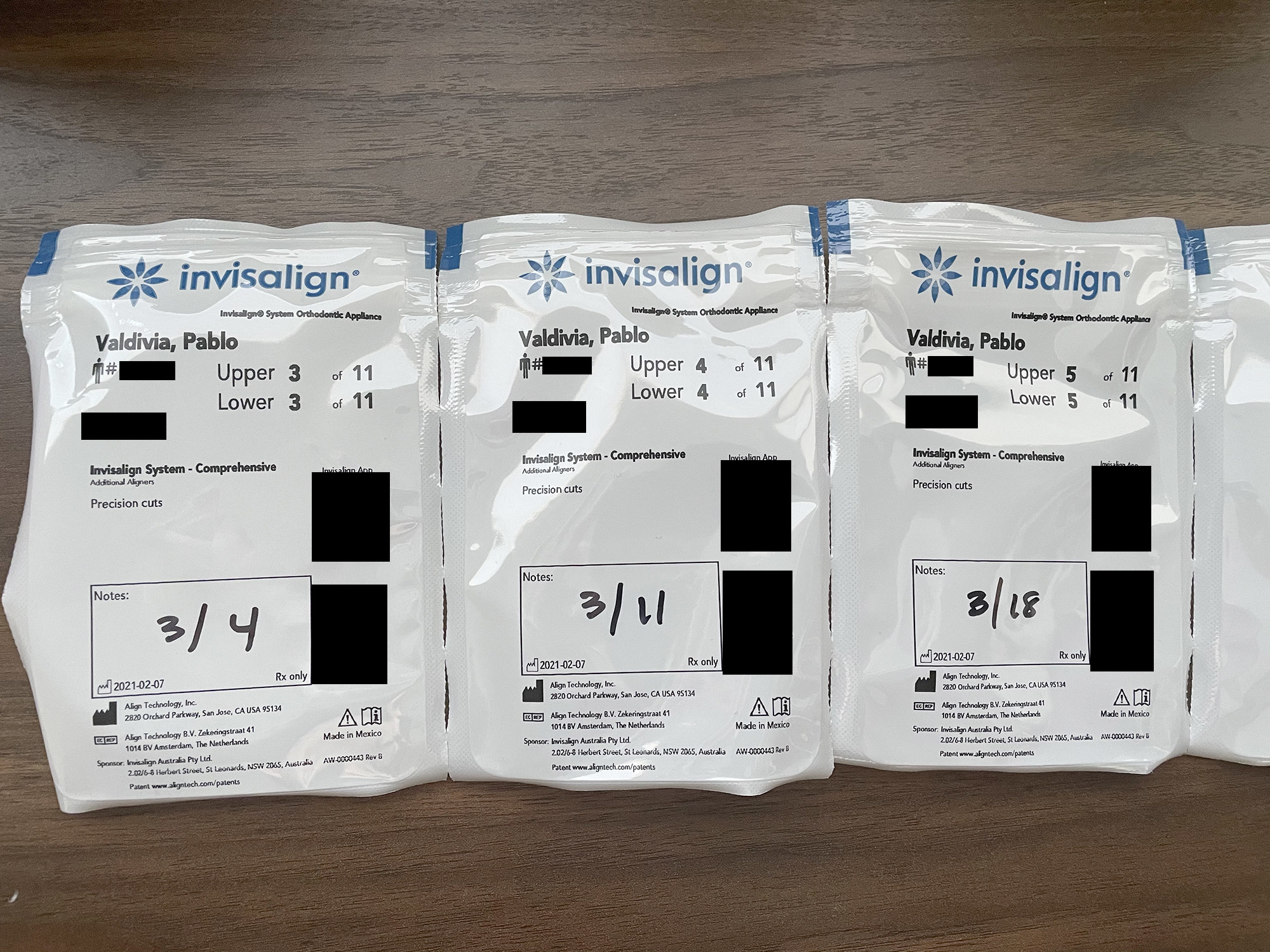 Three Invisalign trays in their plastic bags with dates on them