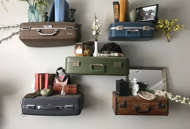 five vintage suitcases hung on the wall holding knicknacks