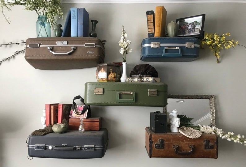 five vintage suitcases hung on the wall holding knicknacks