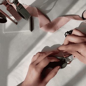 Model inserting small keys into a metal rod in small colorful leather holder