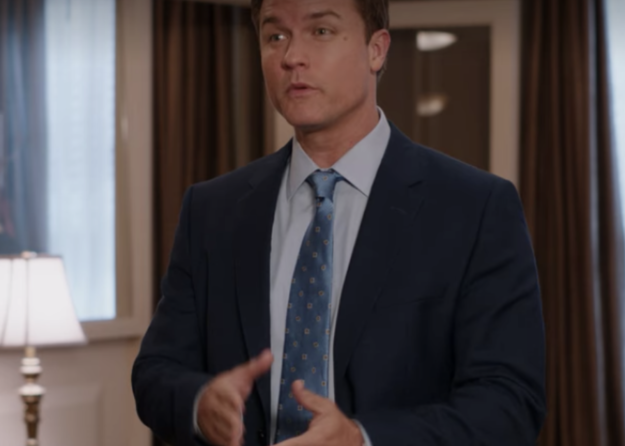 A man is dressed in a suit standing in the middle of an office