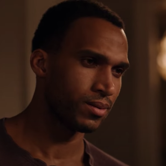 A man is in a bedroom, looking down in a romantic way