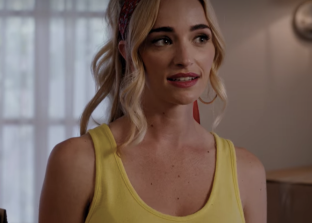 A woman is wearing a tank while smiling in the living room