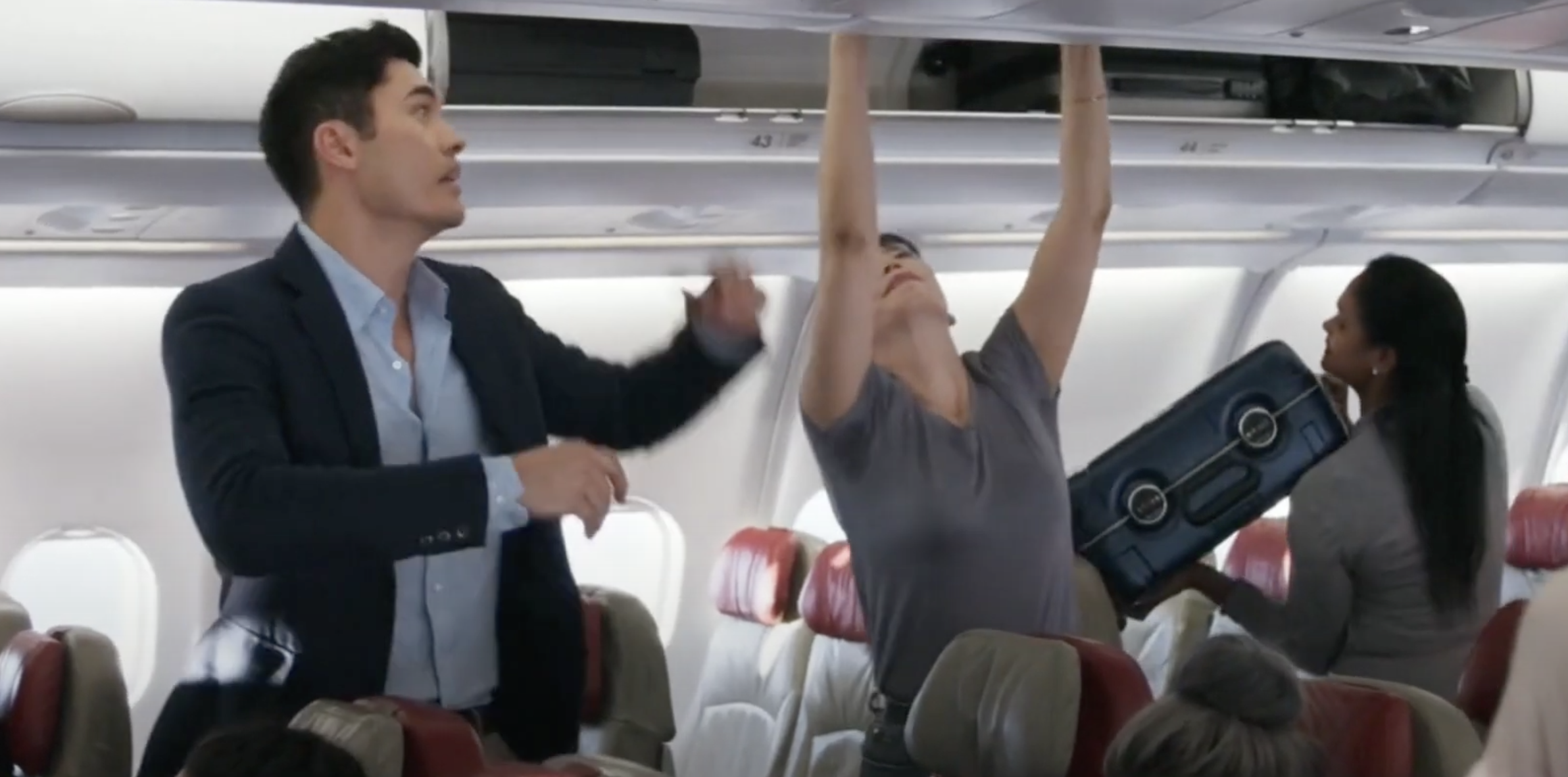 Nick helping a woman lift her bag in &quot;Crazy Rich Asians&quot;