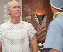 A gif of John Lithgow from 3rd Rock from the Sun wearing a hospital gown and shouting, oh my god i&#x27;m gorgeous!