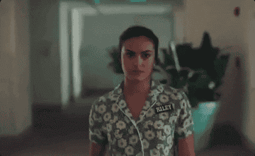 Camila Mendes walking down a hall and ripping off her dress into a new dress