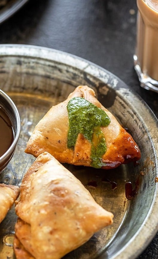 Fried samosas topped with green sauce.