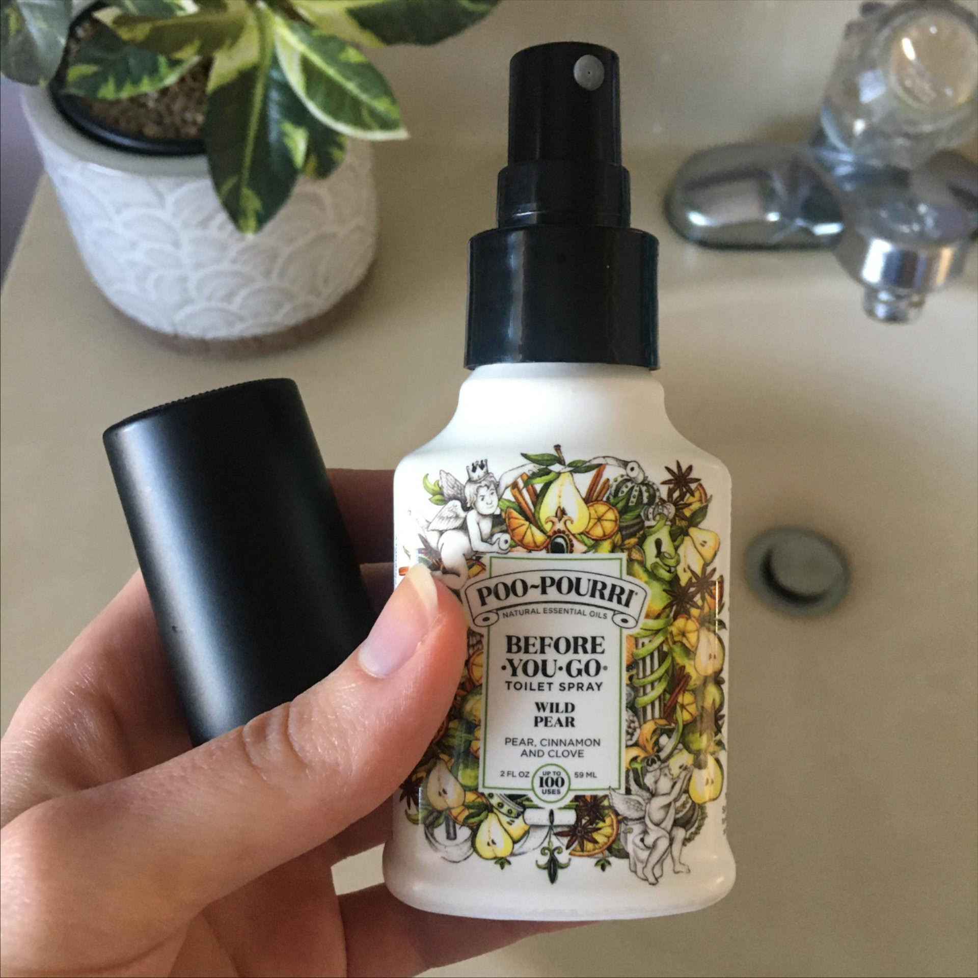 Reviewer holding a spray bottle of wild pear poo-pourri