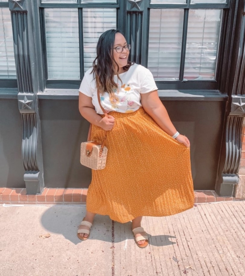 A person wearing a bright orange maxi skirt and a white top