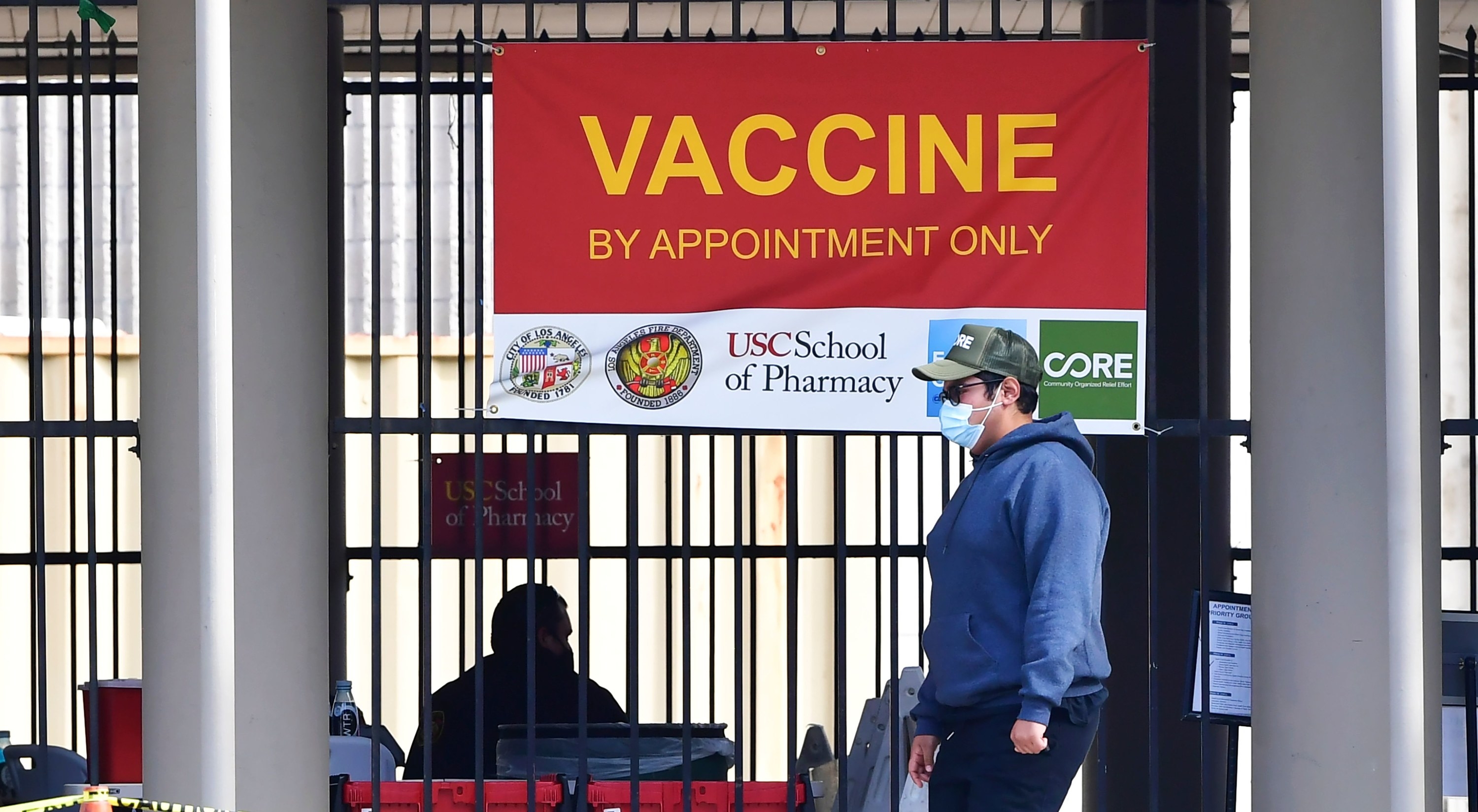 A sign reading &quot;vaccine by appointment only&quot; hangs on a gate