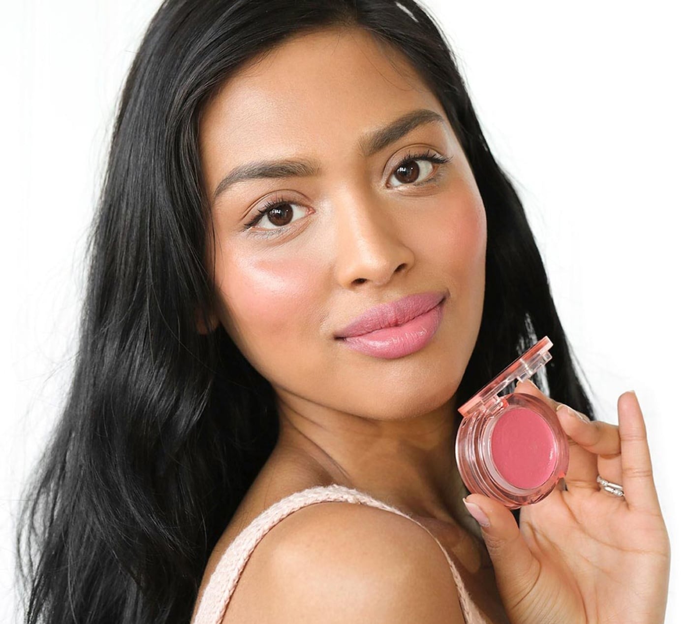 person holding the product with it on her cheeks and lips too