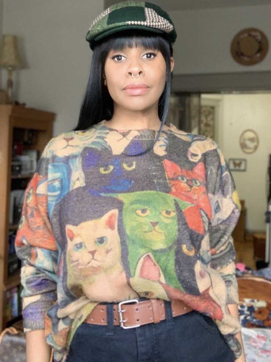 Person is wearing a graphic sweater with various cats on it